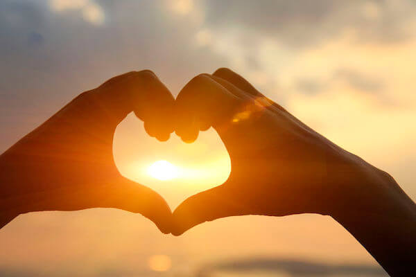 sunset wedding - hands making a heart on the beach at sunset