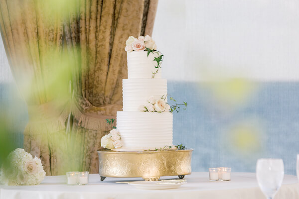 Tampa wedding - Tampa wedding reception - Rusty Pelican Restaurant wedding reception - butter cream wedding cake - wedding cake - three tiered wedding cake - three tiered white wedding cake - wedding cake on gold riser - 