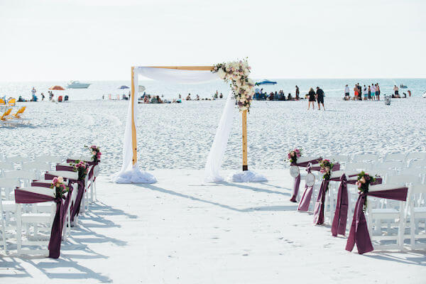 Special moments Event Planning x- Clearwater Beach wedding - Clearwater Beach wedding planner - Sandpearl Resort wedding - beach wedding ceremony - beach wedding ceremony with purple decor - white garden chairs - chairs with purple sashes - wooden arbor with flowers- Gold of Mexico wedding