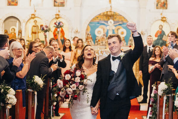 Christina and Kyle, bride and groom, celebrate at the end of their traditional Greek wedding ceremony