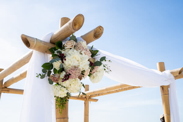 wedding structure - bamboo wedding arch - pink and white ceremony flowers - beach wedding ceremony