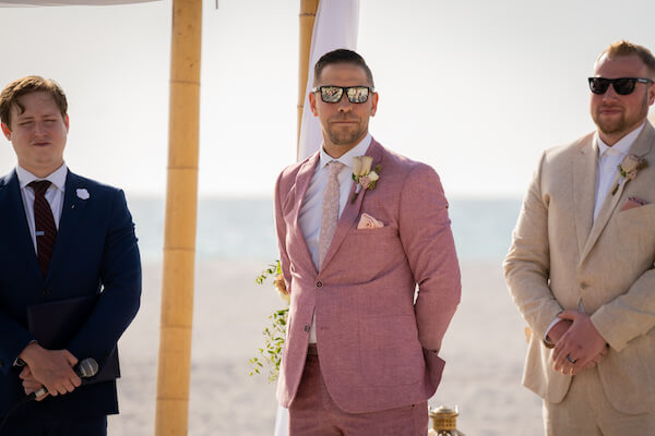 groom in rose colored suit - groom waiting for bride- groom standing on beach waiting for bride - Florida beach wedding