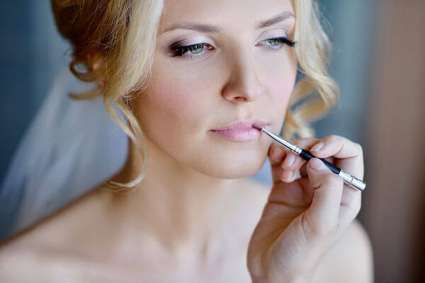 makeup artist applying bride's lipstick - 