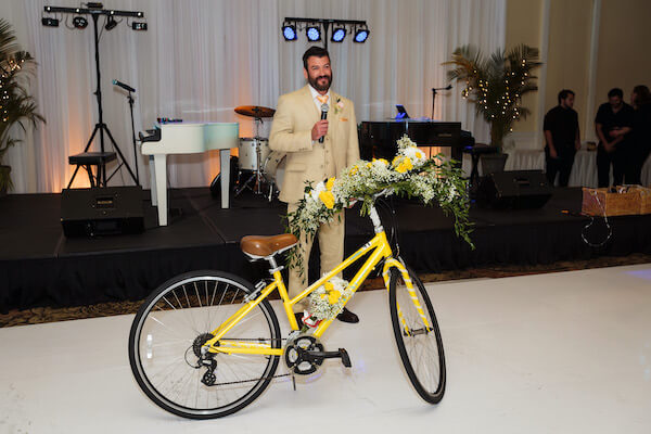 groom presenting his bride with a yellow bicycle just like the ones they rode on their first date