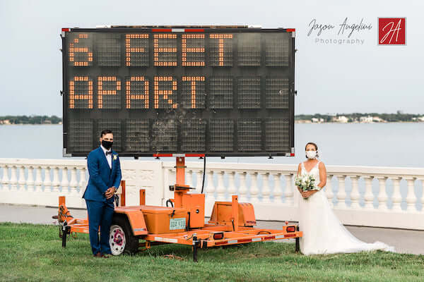 bride and groom following direction on digital billboard and keeping six feet apart