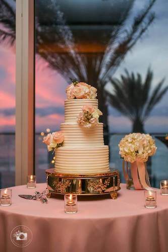 Tampa weddings – wedding cakes – cake stands – displaying your wedding cake - white wedding cake on a silver stand in front of a window at sunset