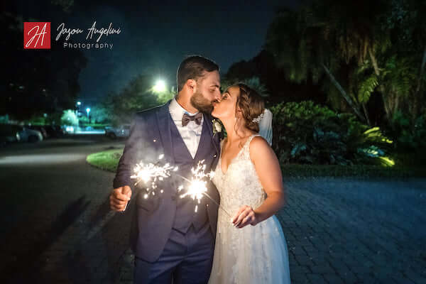 bride and groom with sparklers kiss goodnight