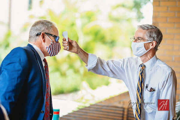 Church volunteer taking wedding guests temperature before wedding ceremony