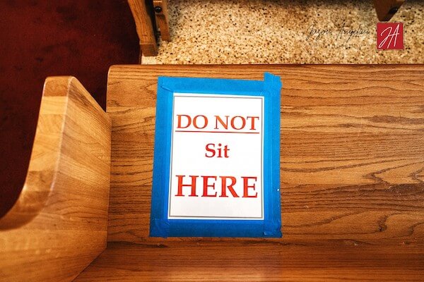 DO NOT Sit HERE sign blocks off pews to promote social distancing