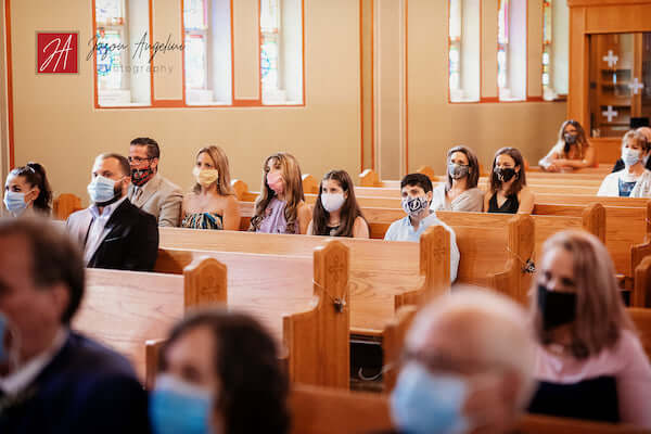 wedding guests inside a church sitting socially distant and wearing masks