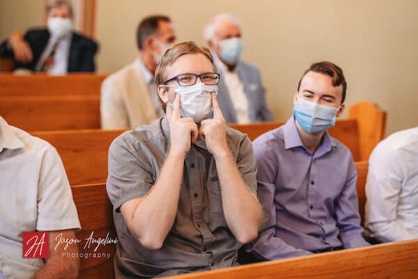 a wedding guest smiling through his mask during a wedding ceremony