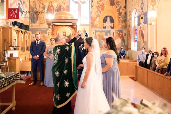 bride and groom wearing crowns in Gree  social distancingwhile practicingk Orthodox wedding