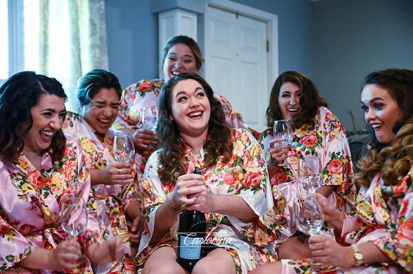 bride and her bridesmaids  in matching floral robes drinking champagne