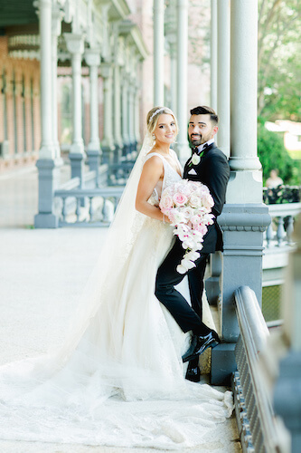 bride and groom leaning against a metal railing on the porch of the University of Tampa