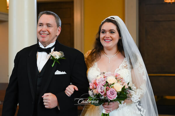 Smiling bride walking down the aisle with her father