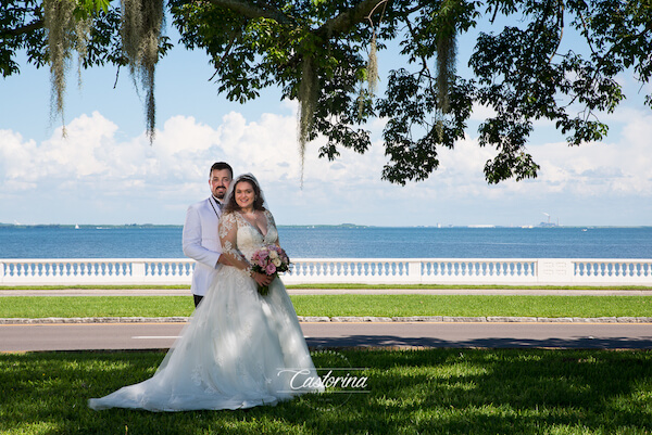 bride and groom posing for photos along Bayshore  Boulevard in front of Tampa Bay