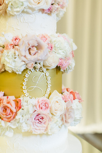 cold and champagne wedding cake with monogram and pink and blush flowers