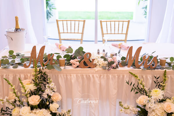 rectangular sweetheart table with white floral centerpieces and gold Mr and Mrs letters