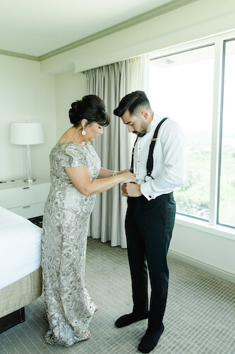 Mother of the groom assisting him in getting dressed