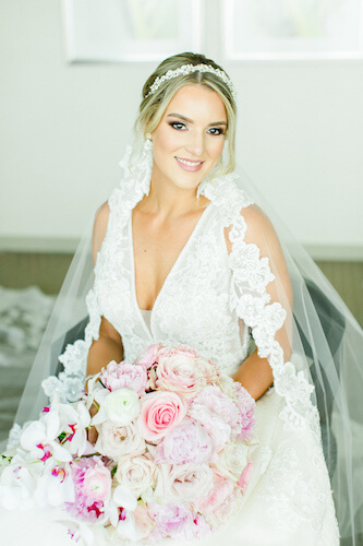 bride wearing a lace wedding gown with a deep V neckline, mantilla and crystal headband