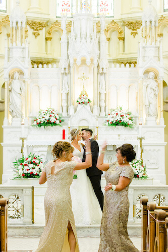 Mothers of the bride and groom high living in the middle of the aisle as their children marry