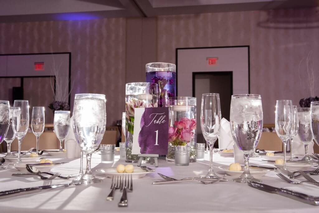 wedding reception table set with custom table numbers and floating candles with submerged flowers