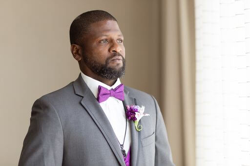 groom in a grey suit with purple vest and bow tie