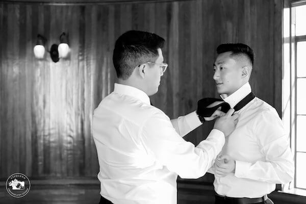 groomsmen helping groom fix his tie