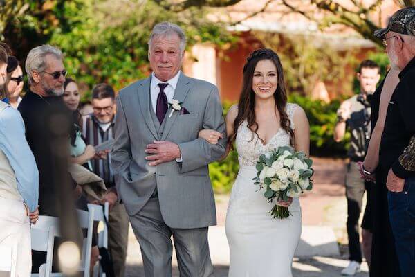 father of the bride crying as he escorts his daughter down the aisle at her wedding