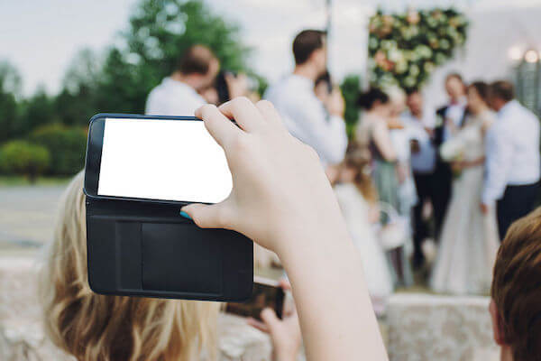 unplugged wedding with a guest taking a photo of the bride on their cell phone