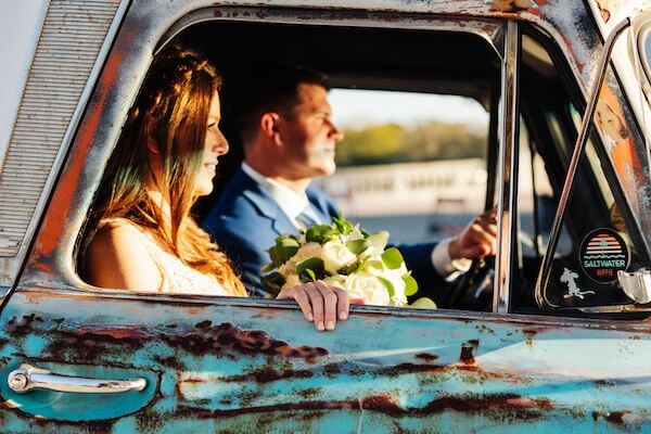 newlyweds taking photos inside a vintage pickup truck