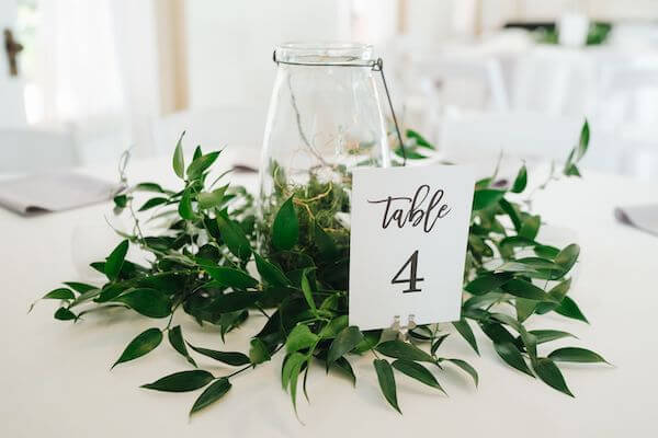 wedding centerpiece of greenery hurricane gloms and fairy lights