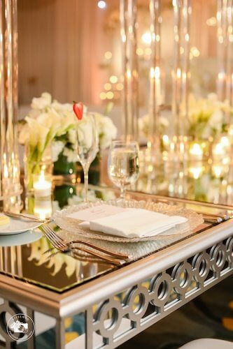 Fairytale wedding decor with mirrored tables, glass charger plates and white floral arrangements