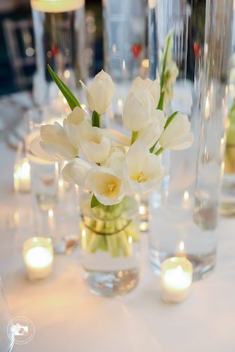 fairytale wedding reception with a vase of white tulips and votive candles