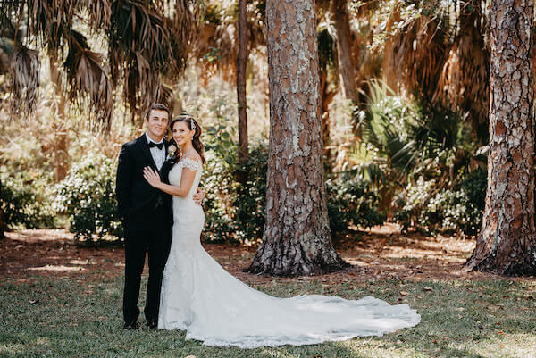 Bride and groom pose for wedding photos under a tree with hanging Spanish moss