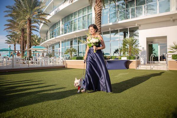 bridesmaid in navy blue dress entering with the bride and groom's dog