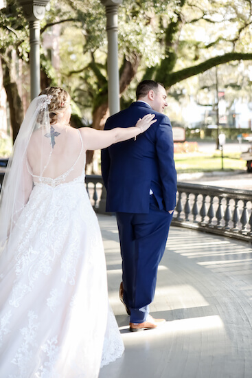 bride tapping her groom on the shoulder during their first look photos at University of Tampa