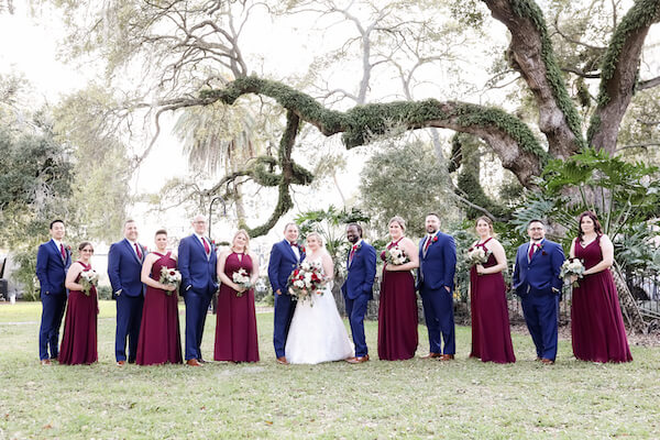 Tampa bride and groom posing for photos with their wedding party iwearing navy blue and burgundy