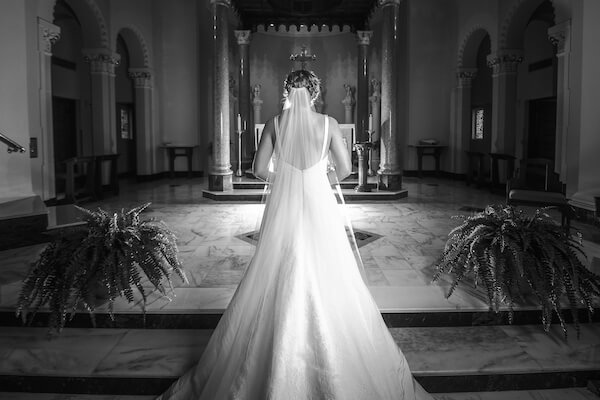 black and white photo from behind a bride standing at the altar