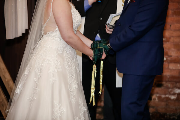 brid mand groom with their hands wrapped in green tartan cloth during a hand fasting