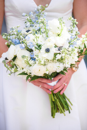 Saint Petersburg bride carrying a bouquet of white ranunculus, anemone and blue delphinium