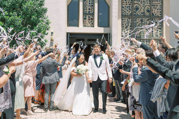 Tampa newlyweds being cheered on by wedding guests with white ribbon wands