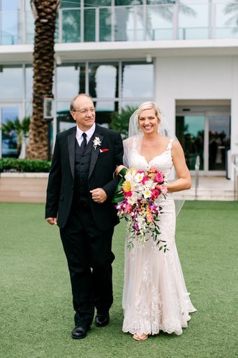 smiling bride being escorted down the aisle by her father