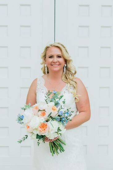 Destination wedding bride wearing a soft lace wedding gown with a coral and light blue bridal bouquet