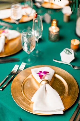 gold chargrrplates with white napkins and purple orchids