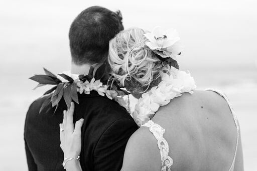 back and white photo taken from behind newlyweds wearing Hawaiian wedding leis