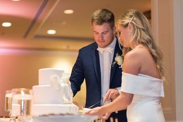 bride and groom cutting their white wedding cake