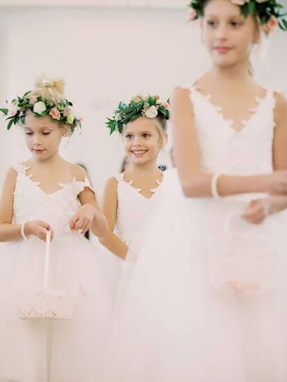 three adorable flower girls wearing lace dresses and wearing pink and white flower head pieces