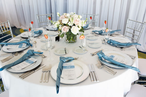 wedding reception set with silver charger plates, ice blue napkins and blue toned menu cards