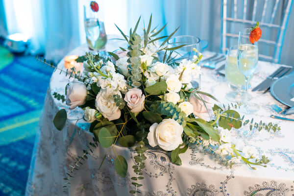 sweetheart table draped with a sequin textured linen and decorated with blush and white flowers